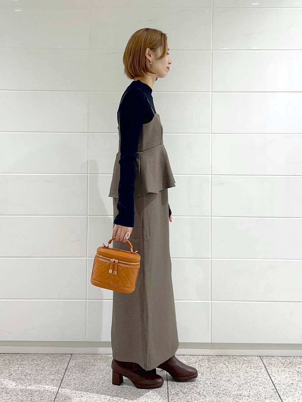 ブラウン系のブーツ、ブラウン系のワンピース、オレンジ系のショルダーバッグを着用したレディースの秋コーディネートの2枚目の写真