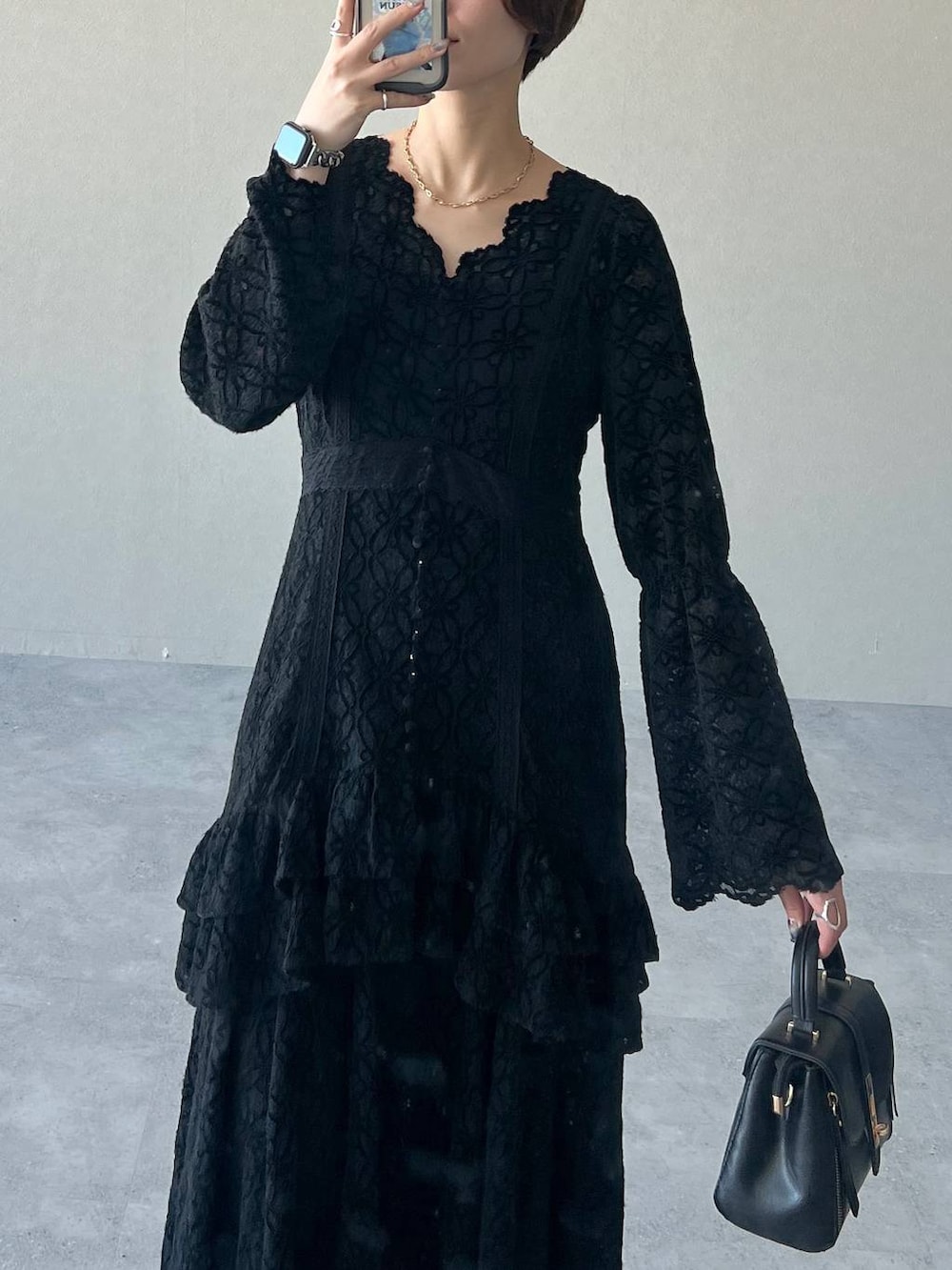 ブラック系のワンピース、パープル系のチェスターコート、ブラック系のブーツを着用したレディースの冬コーディネートの7枚目の写真