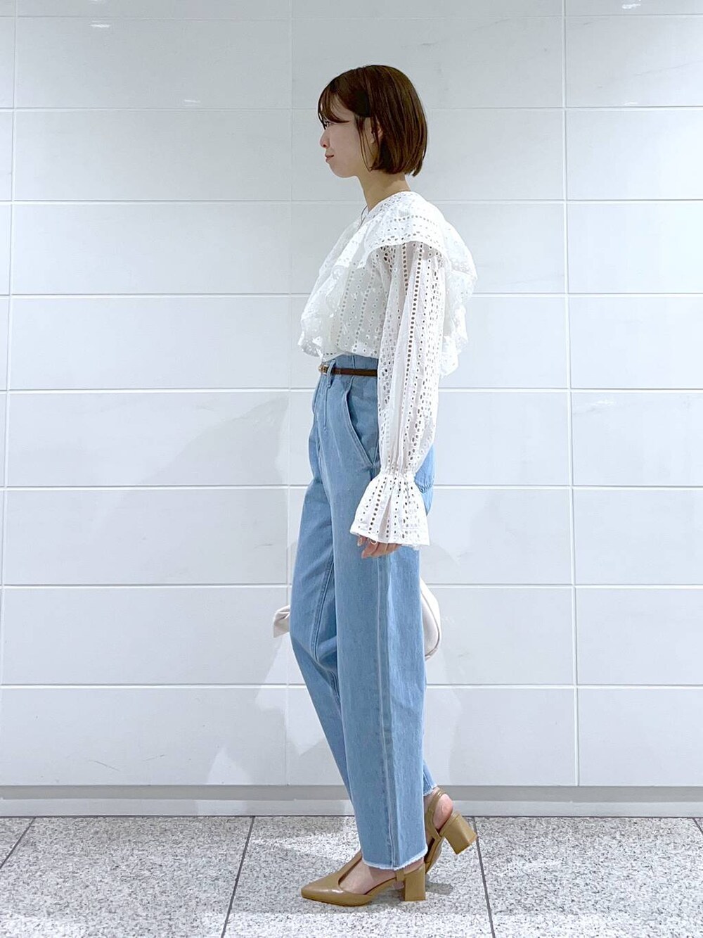 ホワイト系のシャツ/ブラウス、ホワイト系のハンドバッグ、ベージュ系のパンプスを着用したレディースの冬コーディネートの2枚目の写真