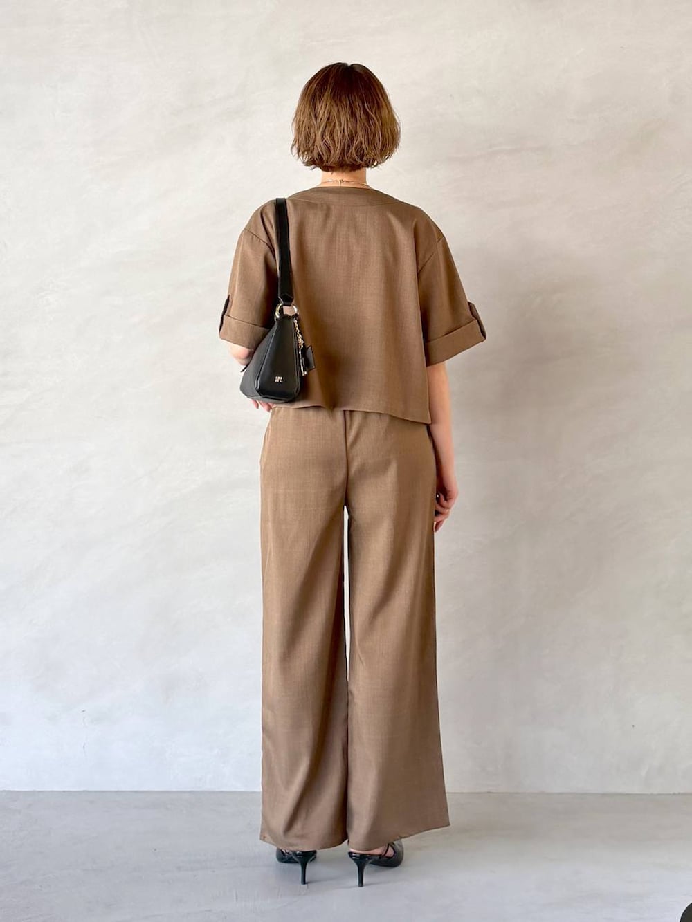 ブラック系のサンダル、ブラック系のショルダーバッグ、ブラウン系のセットアップを着用したレディースの春コーディネートの3枚目の写真