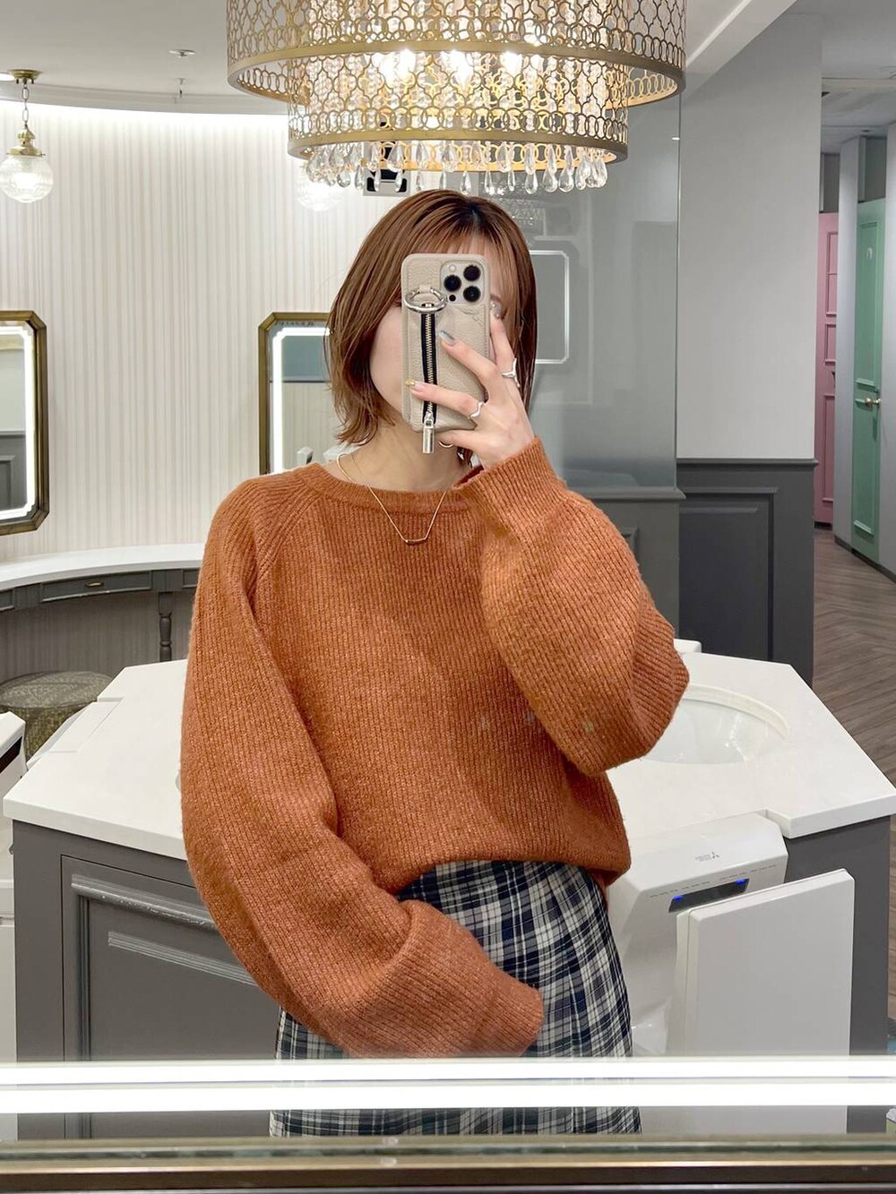 オレンジ系のニット/セーター、ブラック系のブーツ、ホワイト系のスカートを着用したレディースの秋コーディネートの4枚目の写真