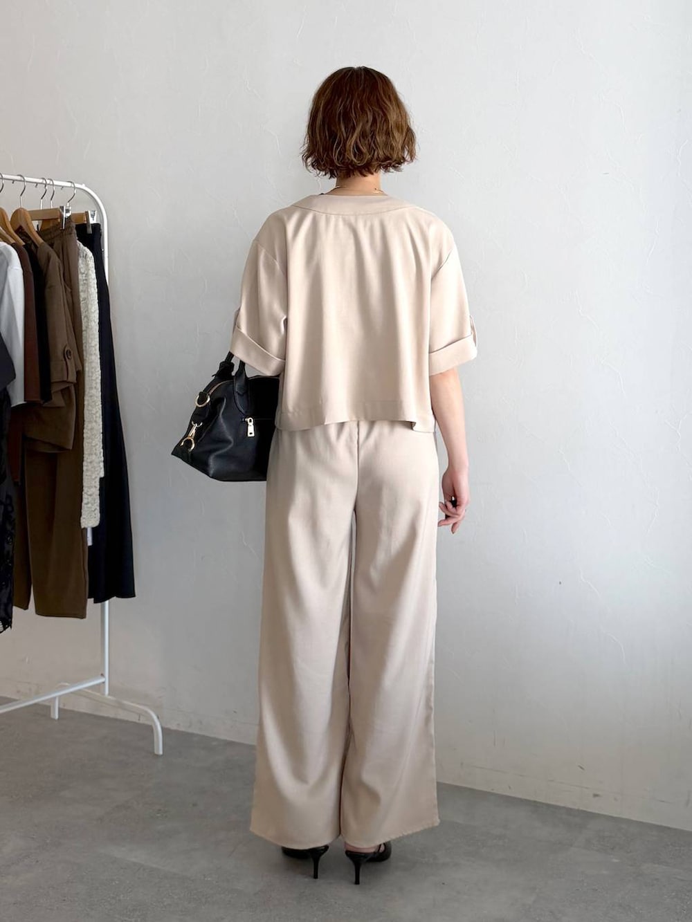 ブラック系のボストンバッグ、ブラック系のサンダル、ホワイト系のセットアップを着用したレディースの春コーディネートの3枚目の写真