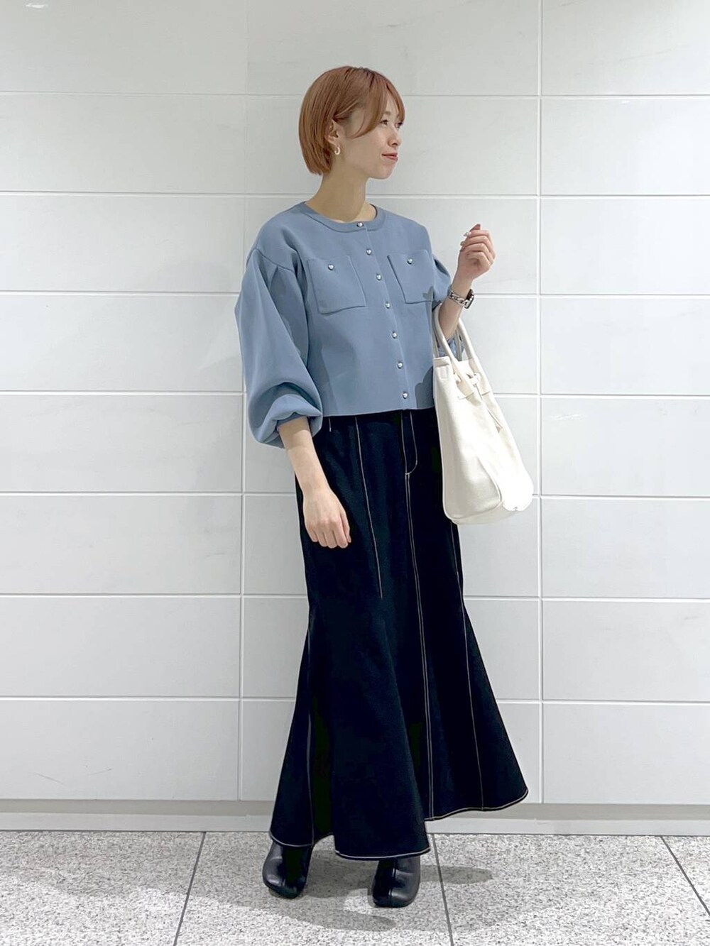 ホワイト系のトートバッグ、ブラック系のパンプス、ブラック系のスカートを着用したレディースの春コーディネートの2枚目の写真