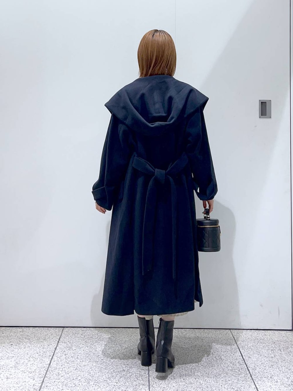 ブルー系のノーカラーコート、ブラック系のブーツ、ベージュ系のワンピースを着用したレディースの秋コーディネートの3枚目の写真