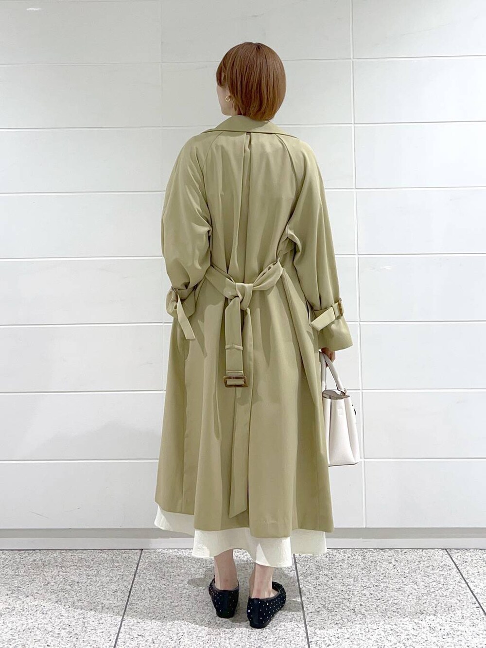 ホワイト系のショルダーバッグ、ベージュ系のトレンチコート、ブラック系のバレエシューズを着用したレディースの春コーディネートの3枚目の写真