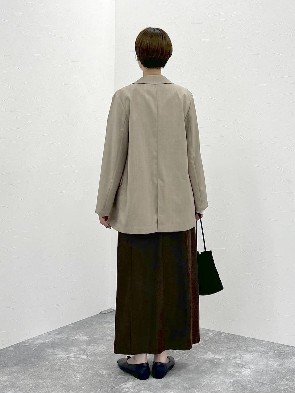 ベージュ系のテーラードジャケット、ホワイト系のTシャツ/カットソー、ブラウン系のスカートを着用したレディースの秋コーディネートの4枚目の写真