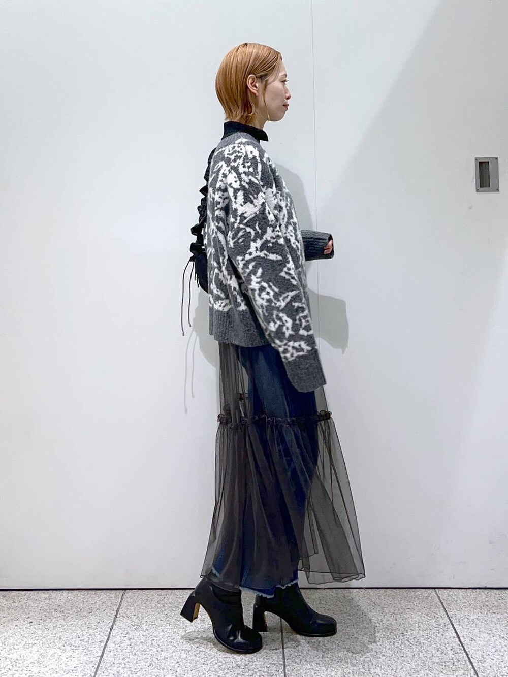 ブルー系のデニムパンツ、ブラック系のハンドバッグ、ブラック系のブーツを着用したレディースの冬コーディネートの2枚目の写真