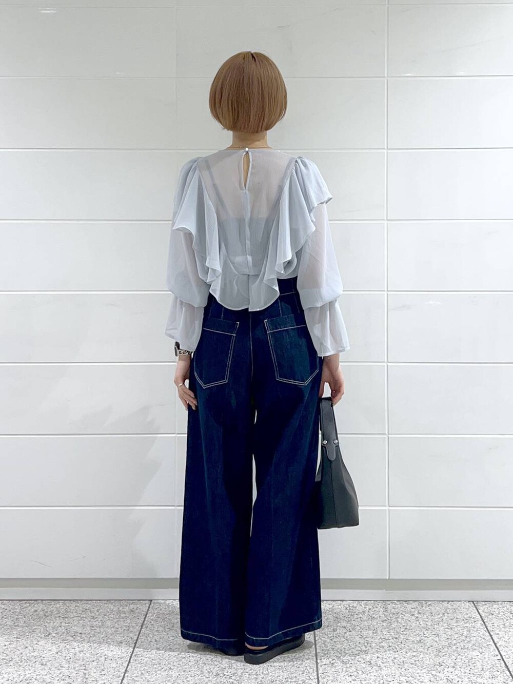 ブラック系のサンダル、ブルー系のデニムパンツ、ブラック系のショルダーバッグを着用したレディースの春コーディネートの3枚目の写真