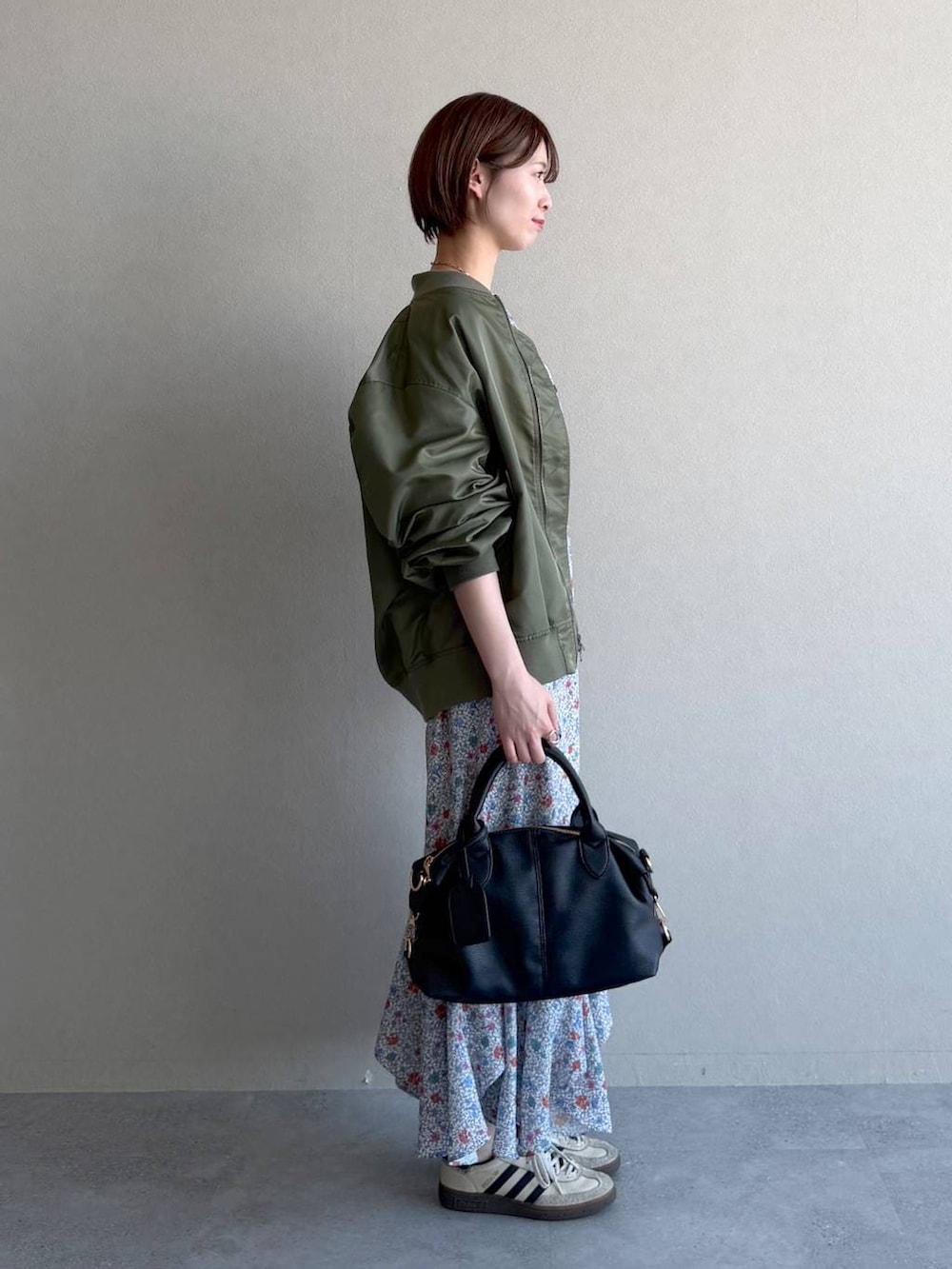 ブラック系のボストンバッグ、ホワイト系のワンピース、グリーン系のMA-1を着用したレディースの冬コーディネートの2枚目の写真