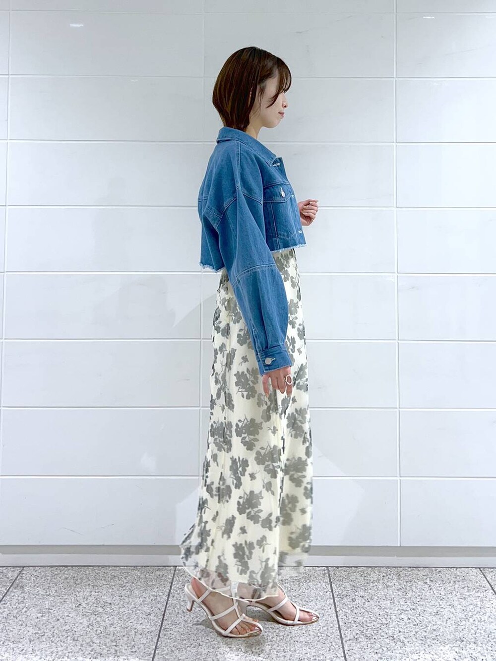 ホワイト系のハンドバッグ、ホワイト系のワンピース、ブルー系のデニムジャケットを着用したレディースの春コーディネートの3枚目の写真