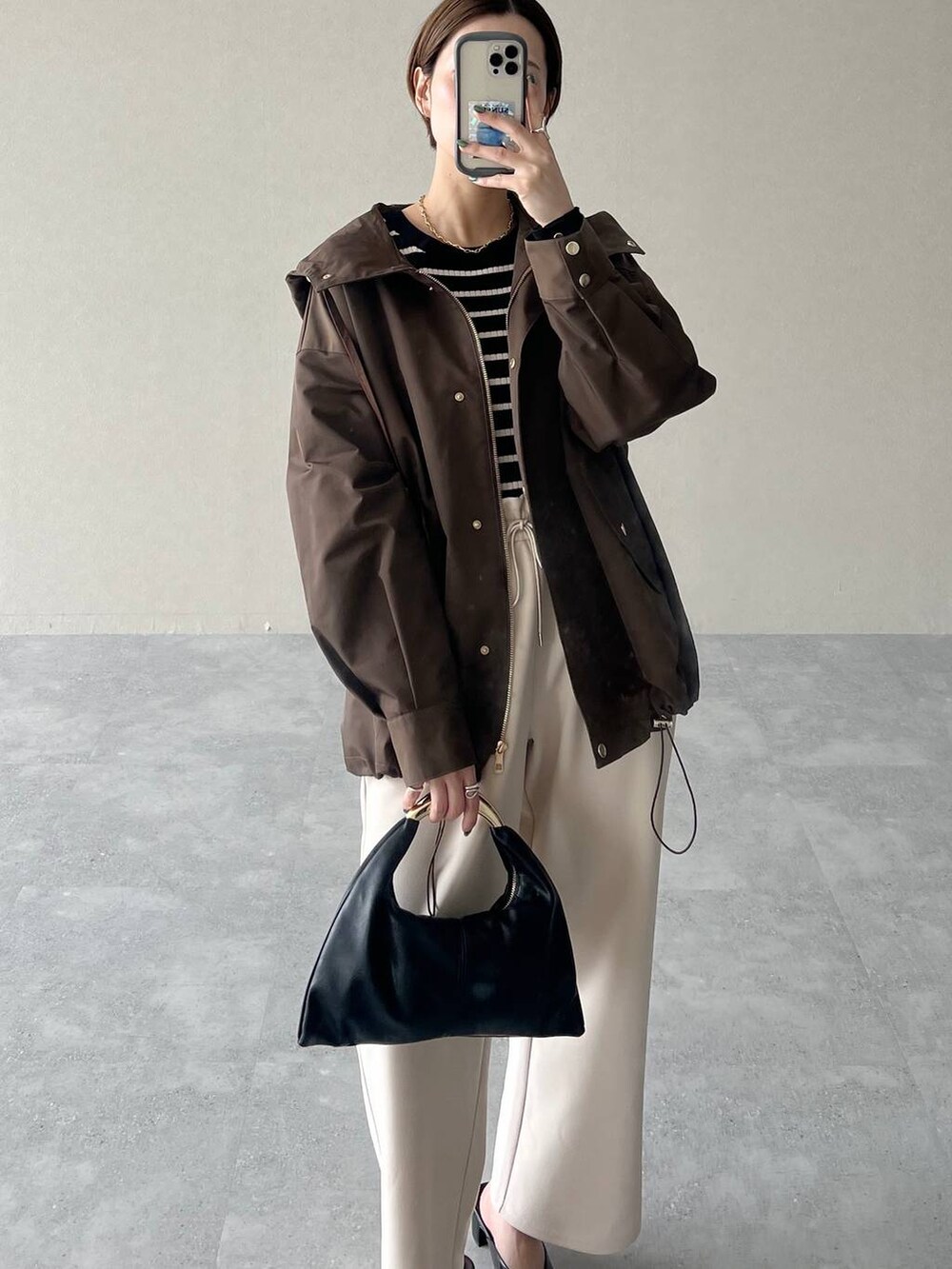 ブラック系のハンドバッグ、ブラウン系のマウンテンパーカー、ブラック系のスリッポンを着用したレディースの秋コーディネートの6枚目の写真