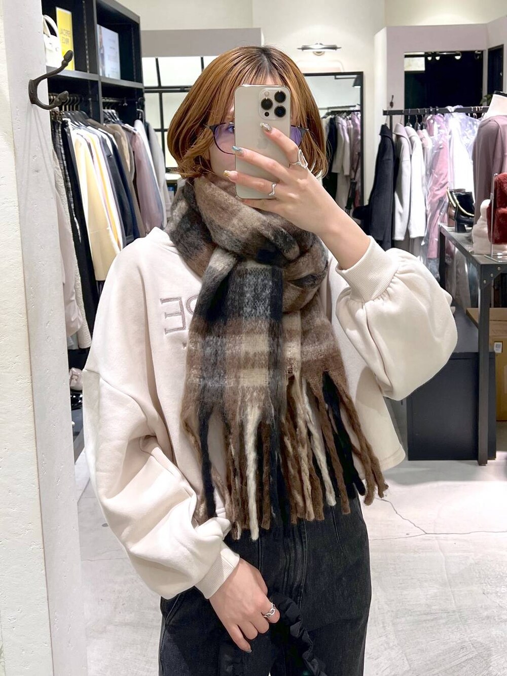 ブルー系のデニムパンツ、ブラック系のハンドバッグ、ブラック系のブーツを着用したレディースの秋コーディネートの4枚目の写真