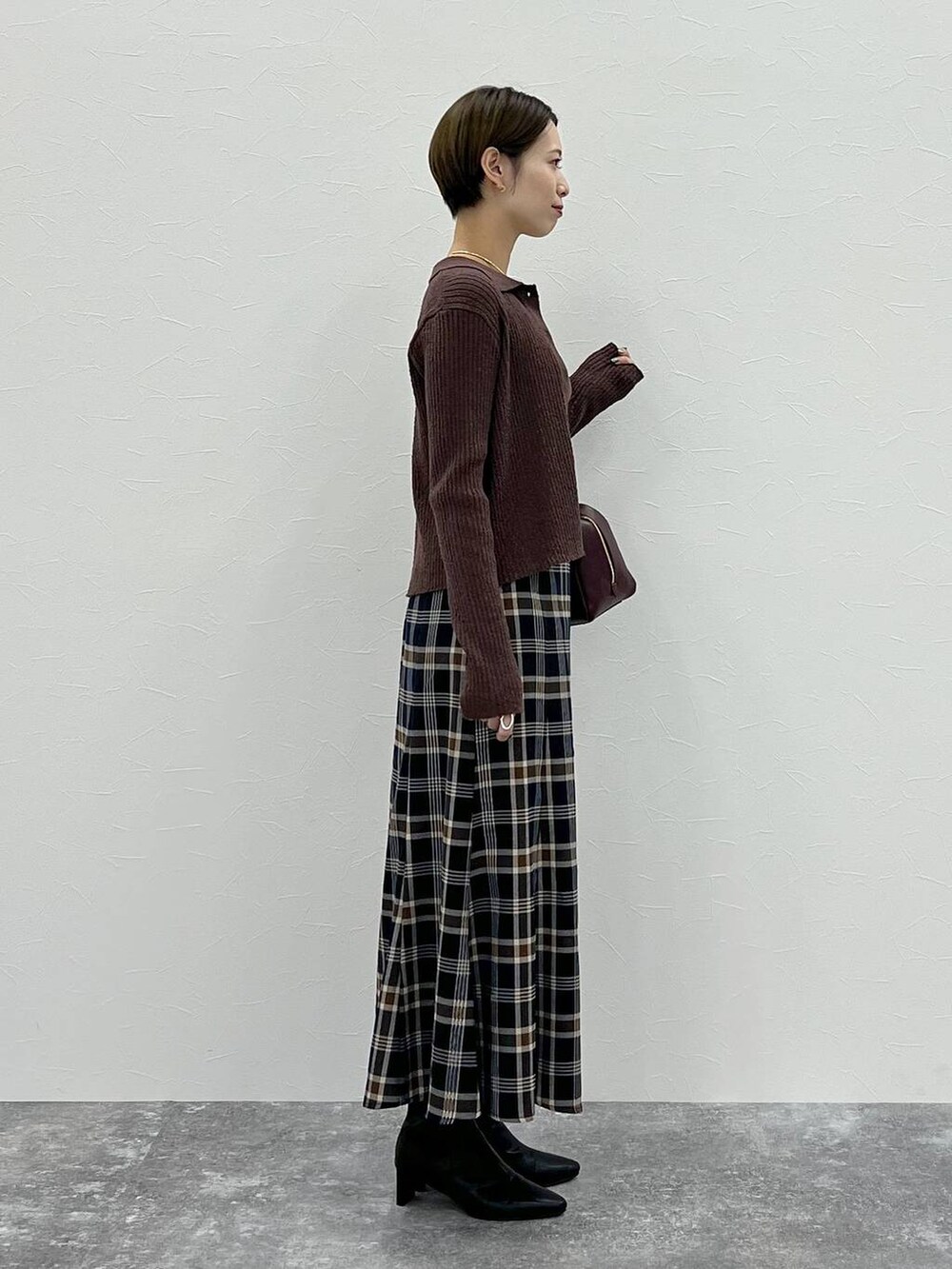 レッド系のハンドバッグ、ブラウン系のカーディガン/ボレロ、ブラウン系のニット/セーターを着用したレディースの秋コーディネートの2枚目の写真