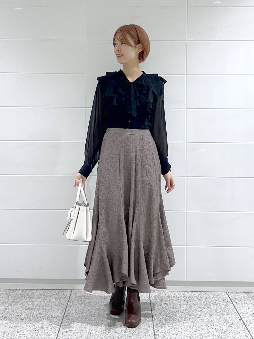 ブラウン系のブーツ、ホワイト系のショルダーバッグ、ブラック系のシャツ/ブラウスを着用したレディースの冬コーディネートの2枚目の写真