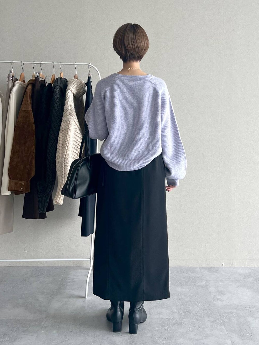 パープル系のニット/セーター、ブラック系のブーツ、ブラック系のトートバッグを着用したレディースの秋コーディネートの3枚目の写真