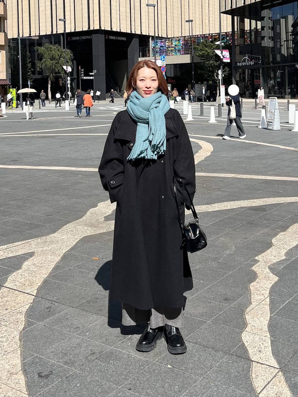 ブラック系のチェスターコート、グレー系のその他パンツ、ホワイト系のニット/セーターを着用したレディースの秋コーディネートの3枚目の写真