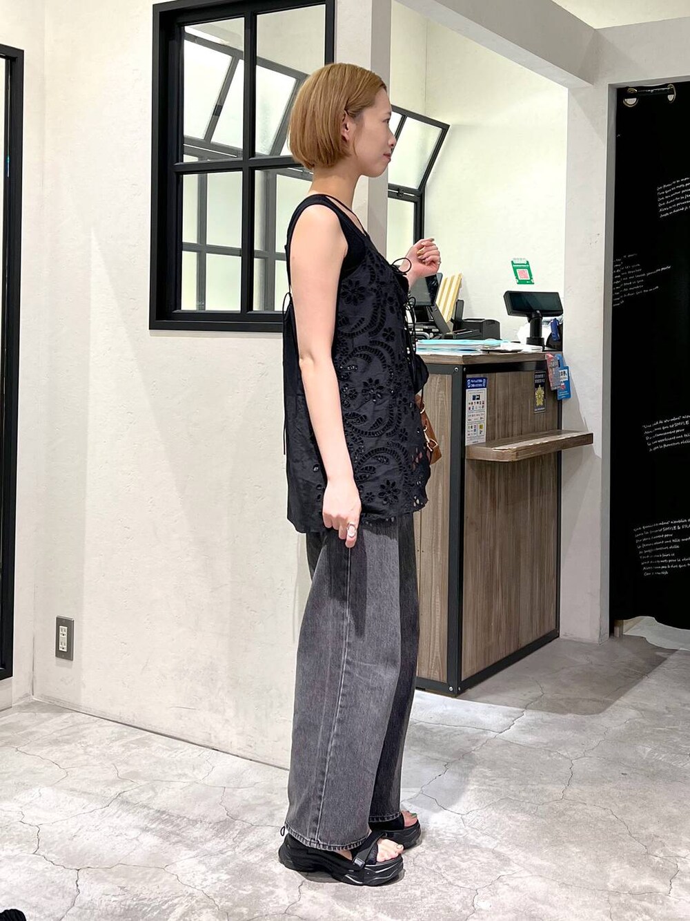 ブラック系のデニムパンツ、ブラック系のタンクトップ、ブラック系のサンダルを着用したレディースの夏コーディネートの2枚目の写真