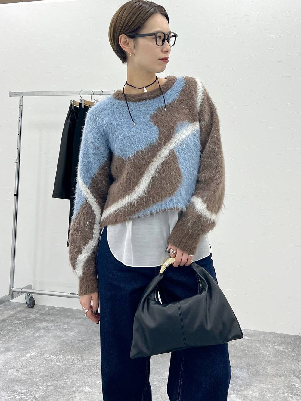 ブラウン系のニット/セーター、ブラック系のハンドバッグ、ブルー系のデニムパンツを着用したレディースの秋コーディネートの5枚目の写真