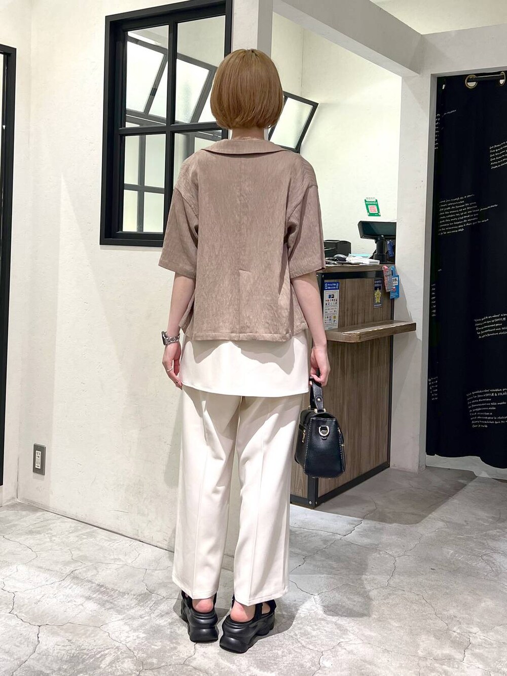 ブラック系のサンダル、ベージュ系のテーラードジャケット、ブラック系のショルダーバッグを着用したレディースの夏コーディネートの4枚目の写真