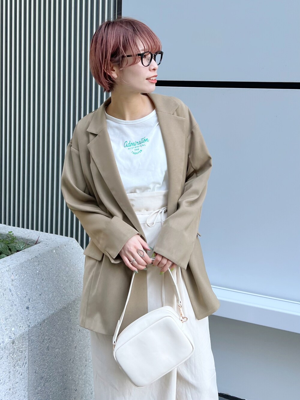 ベージュ系のテーラードジャケット、ホワイト系のスカート、ホワイト系のサンダルを着用したレディースの春コーディネートの4枚目の写真