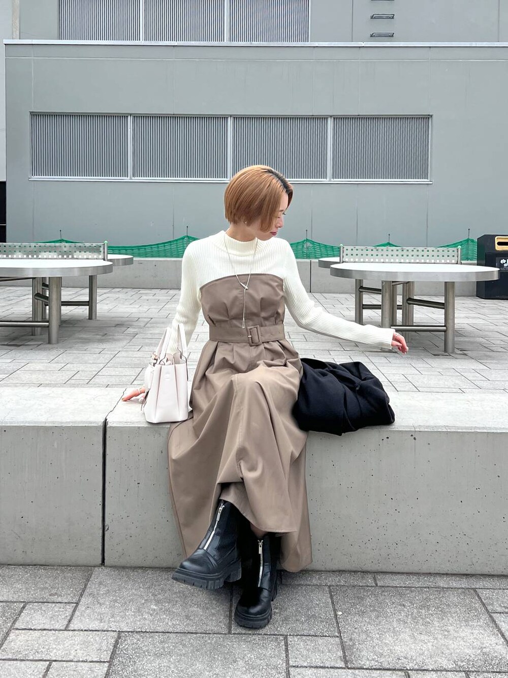 ブラック系のノーカラーコート、ブラック系のブーツ、ホワイト系のショルダーバッグを着用したレディースの冬コーディネートの7枚目の写真