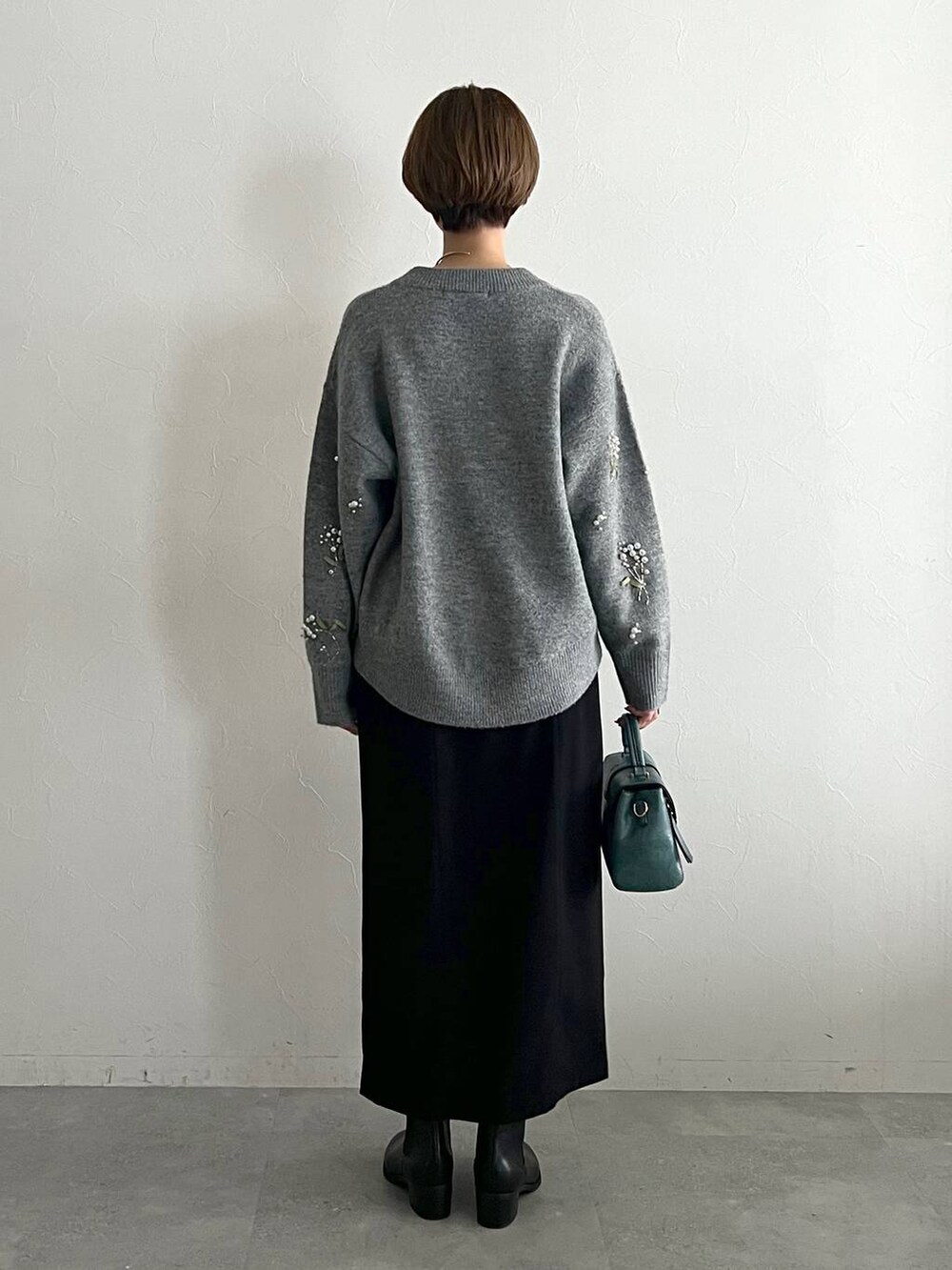 グレー系のニット/セーター、ブラック系のスカート、ブラック系のブーツを着用したレディースの秋コーディネートの3枚目の写真