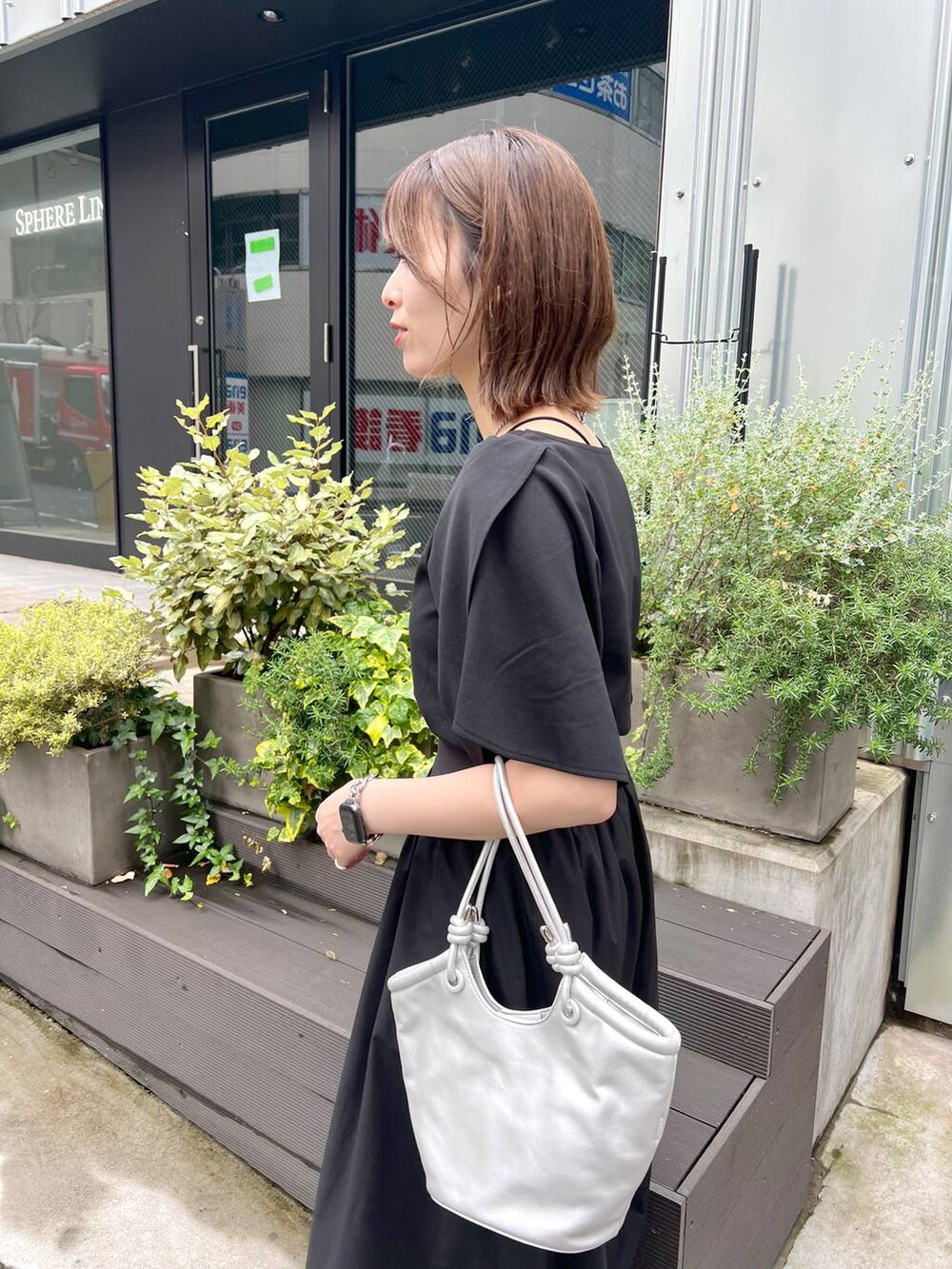シルバー系のハンドバッグ、ブラック系のサンダル、ブラック系のスカートを着用したレディースの春コーディネートの4枚目の写真