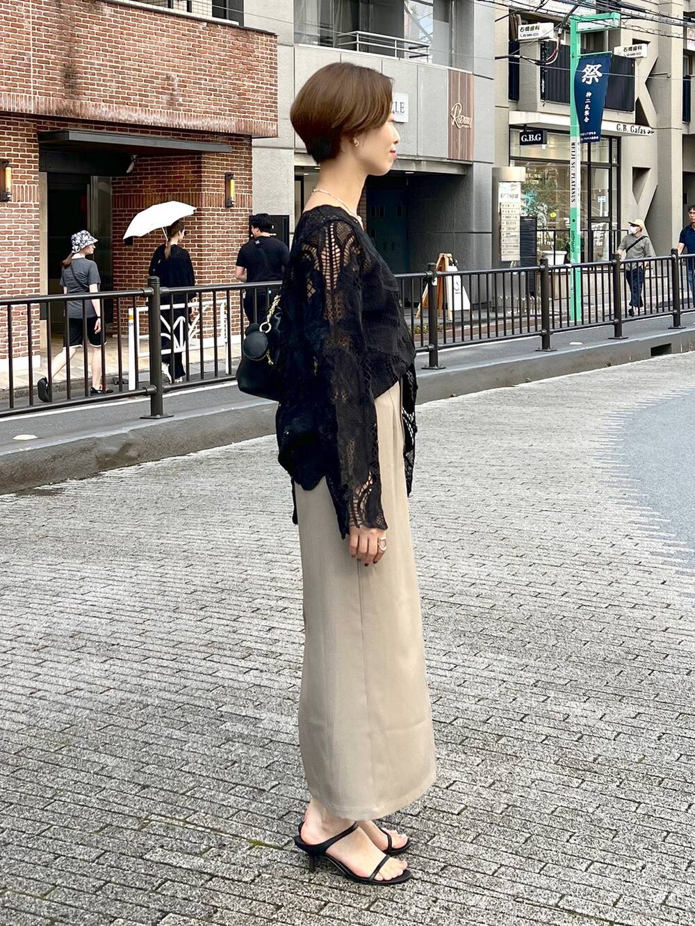 ブラック系のシャツ/ブラウス、ベージュ系のスカートを着用したレディースの秋コーディネートの2枚目の写真