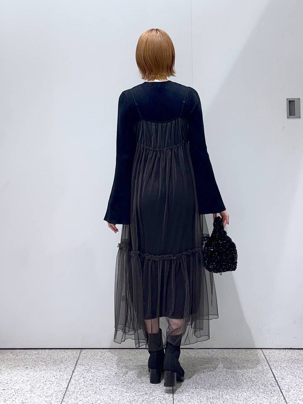 ブラック系のブーツ、ブラック系のハンドバッグ、グレー系のワンピースを着用したレディースの冬コーディネートの3枚目の写真