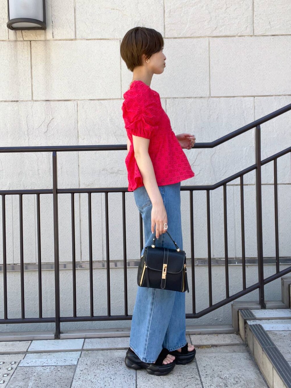 ブルー系のデニムパンツ、ブラック系のサンダル、ブラック系のショルダーバッグを着用したレディースの夏コーディネートの2枚目の写真