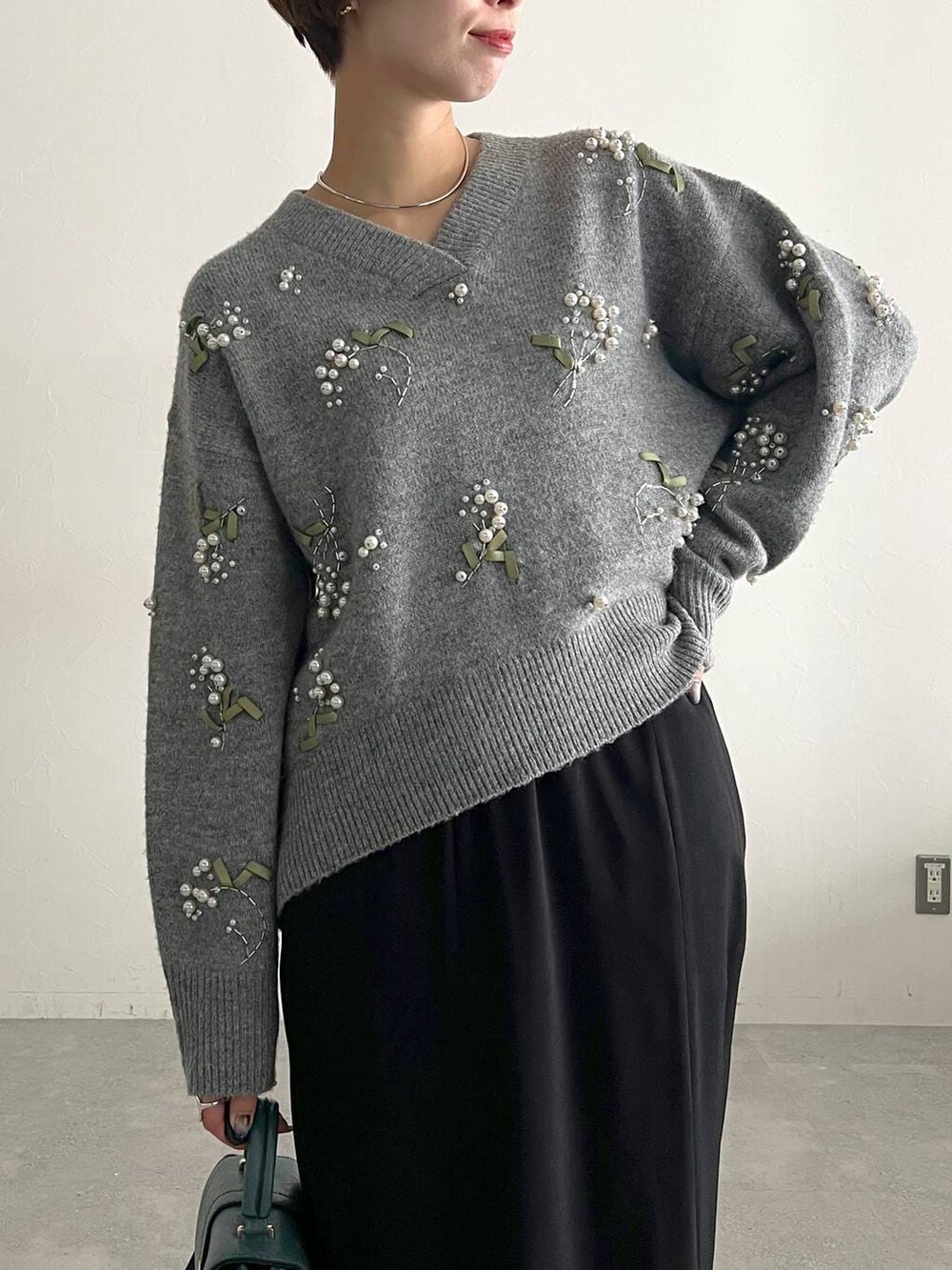 グレー系のニット/セーター、ブラック系のスカート、ブラック系のブーツを着用したレディースの秋コーディネートの4枚目の写真