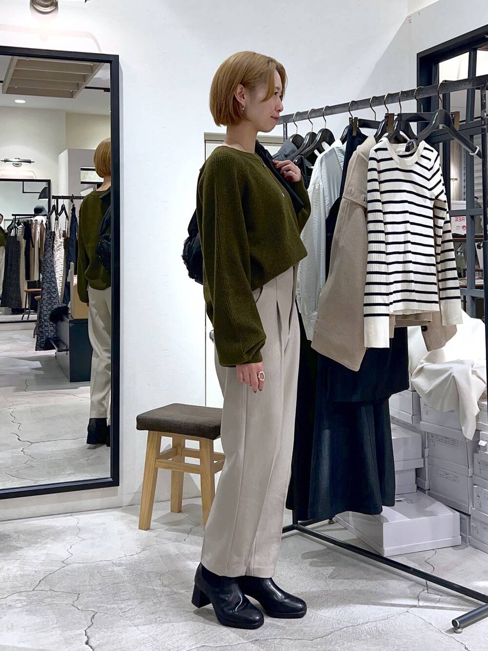 ブラック系のショルダーバッグ、ブラック系のブーツ、グリーン系のニット/セーターを着用したレディースの秋コーディネートの2枚目の写真