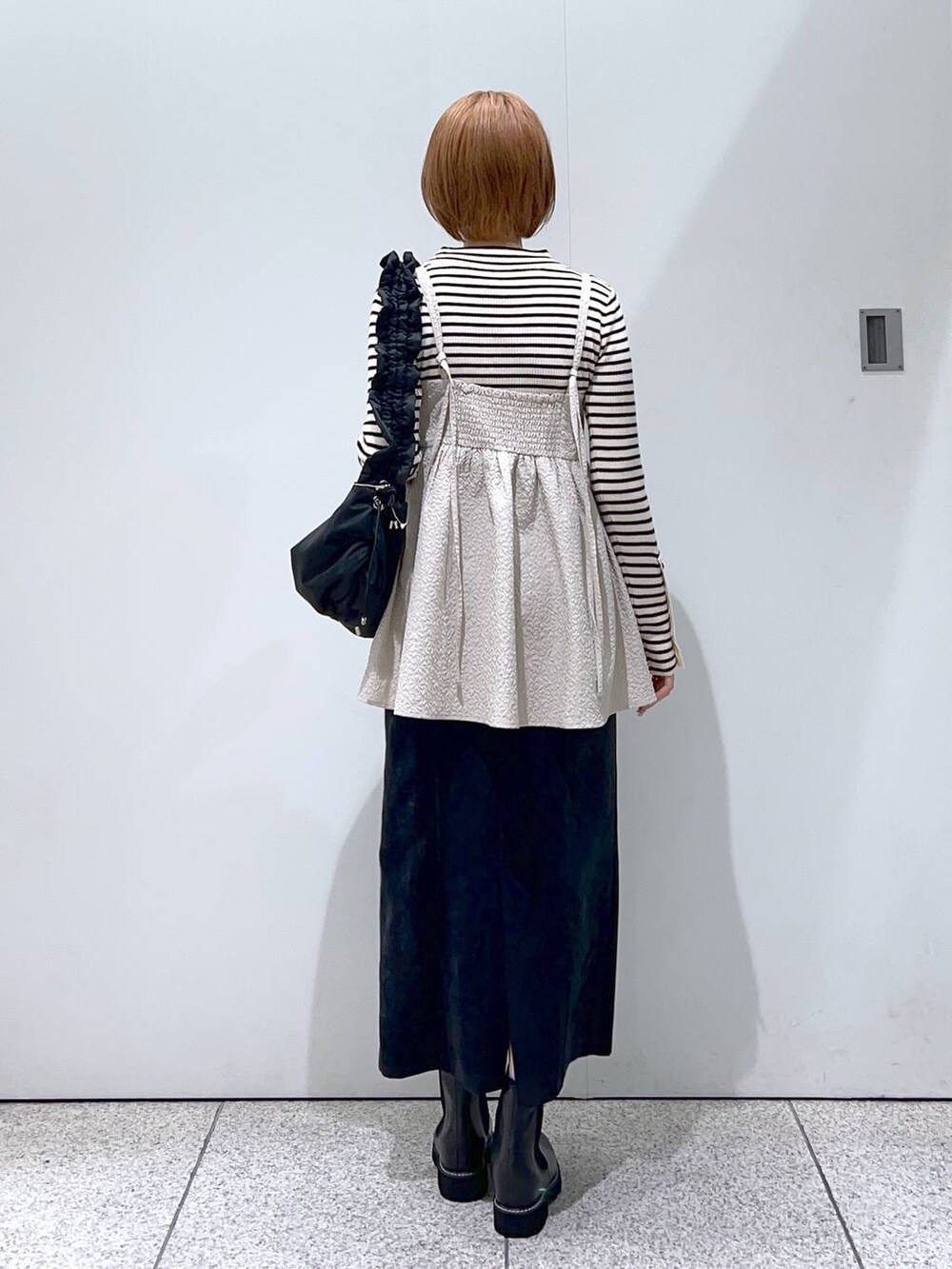 ブラック系のスカート、ベージュ系のキャミソール、ブラック系のハンドバッグを着用したレディースの冬コーディネートの3枚目の写真