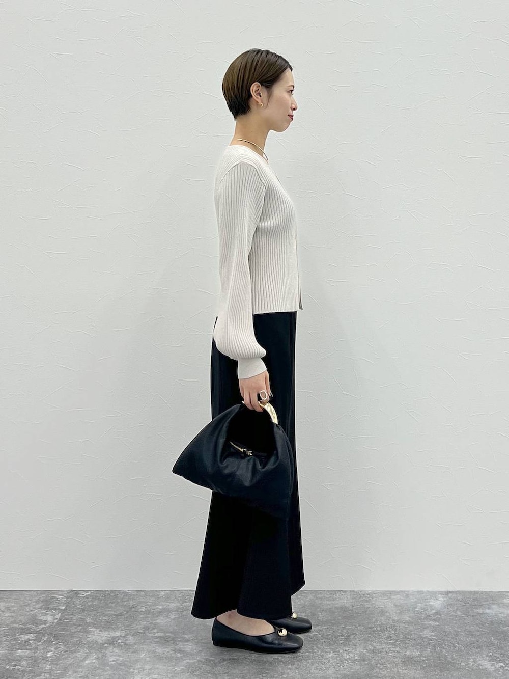 ブラック系のスカート、ブラック系のハンドバッグ、ホワイト系のカーディガン/ボレロを着用したレディースの秋コーディネートの2枚目の写真