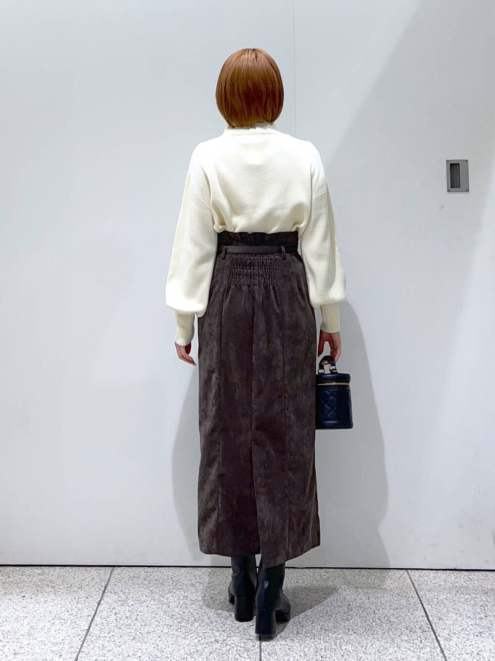 ブラウン系のスカート、ブラック系のブーツ、ブラック系のショルダーバッグを着用したレディースの冬コーディネートの6枚目の写真