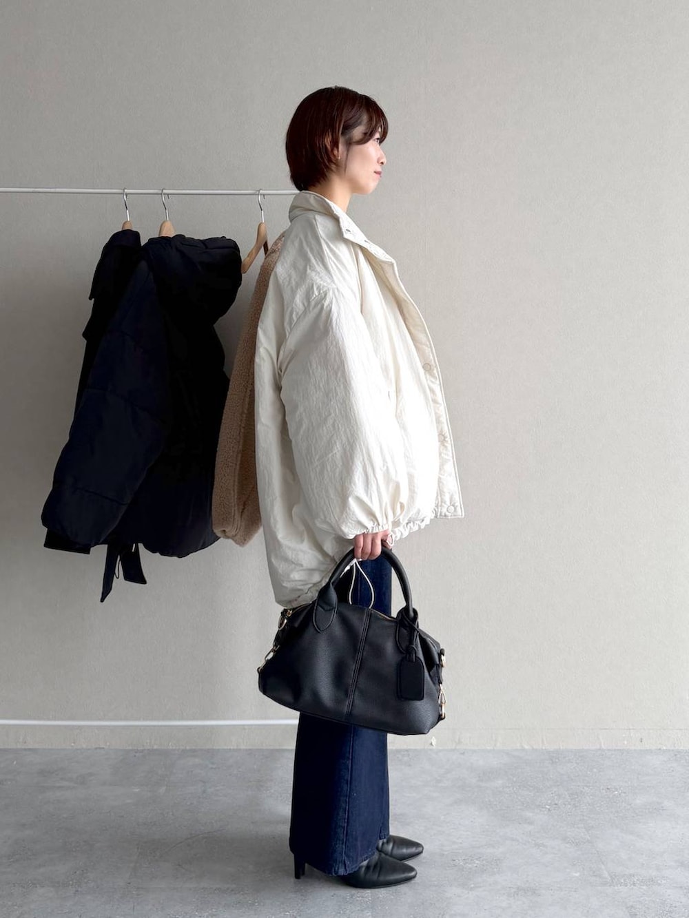 ブルー系のデニムパンツ、ブラック系のボストンバッグ、ホワイト系のナイロンジャケットを着用したレディースの秋コーディネートの2枚目の写真