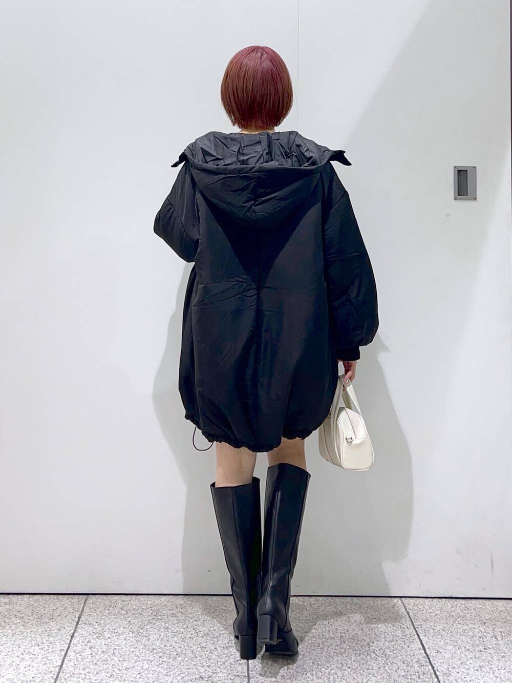 ブラック系のブルゾン、ホワイト系のボストンバッグ、ブラック系のブーツを着用したレディースの秋コーディネートの3枚目の写真