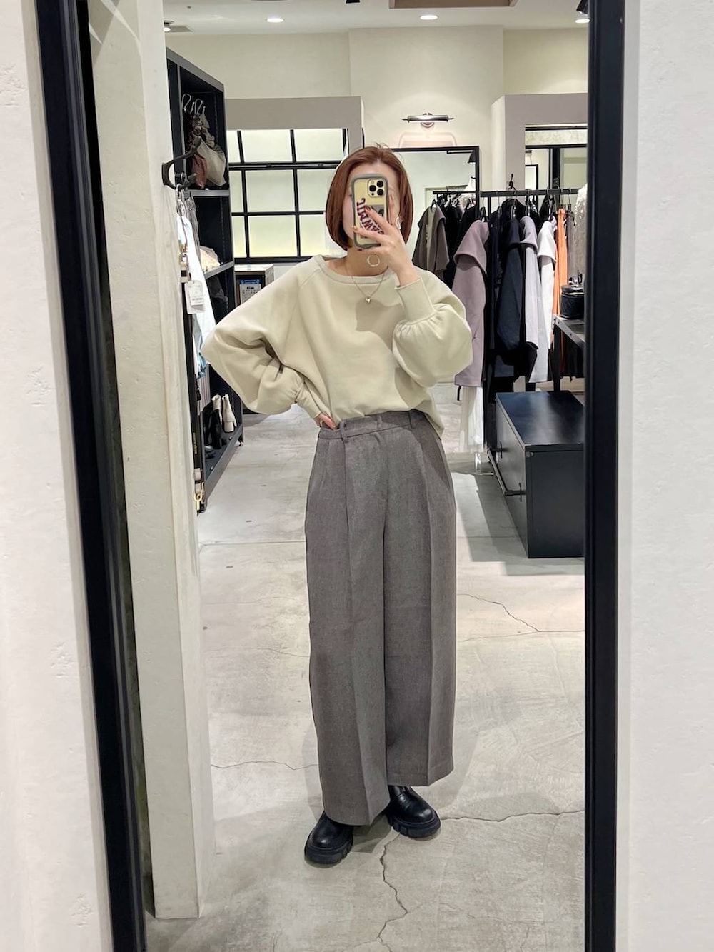 ブラック系のチェスターコート、グレー系のその他パンツ、ホワイト系のニット/セーターを着用したレディースの秋コーディネートの6枚目の写真