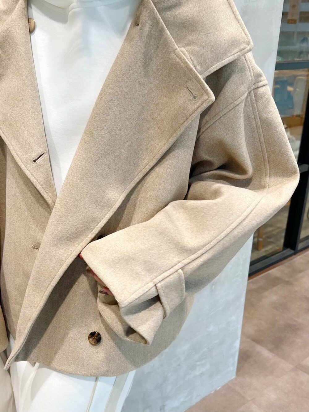 ベージュ系のピーコート、ホワイト系のショルダーバッグ、ブラウン系のブーツを着用したレディースの秋コーディネートの5枚目の写真