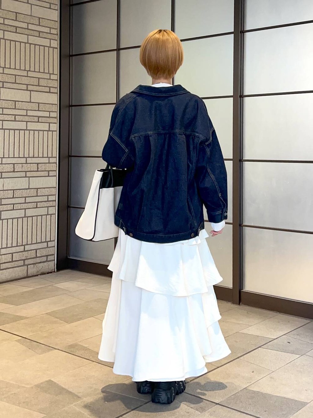 ブラック系のトートバッグ、ホワイト系のスカート、ブルー系のデニムジャケットを着用したレディースの冬コーディネートの3枚目の写真