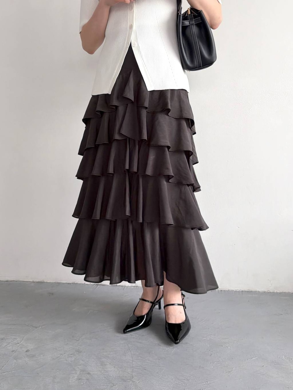 ブラック系のサンダル、ホワイト系のカーディガン/ボレロ、ブラック系のスカートを着用したレディースの春コーディネートの5枚目の写真