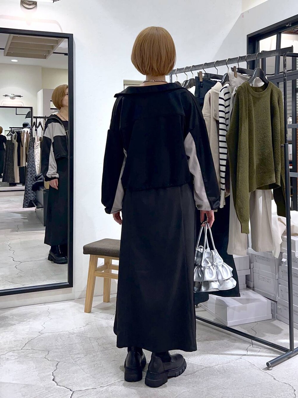 シルバー系のショルダーバッグ、ブラック系のブーツ、ブラック系のワンピースを着用したレディースの秋コーディネートの3枚目の写真