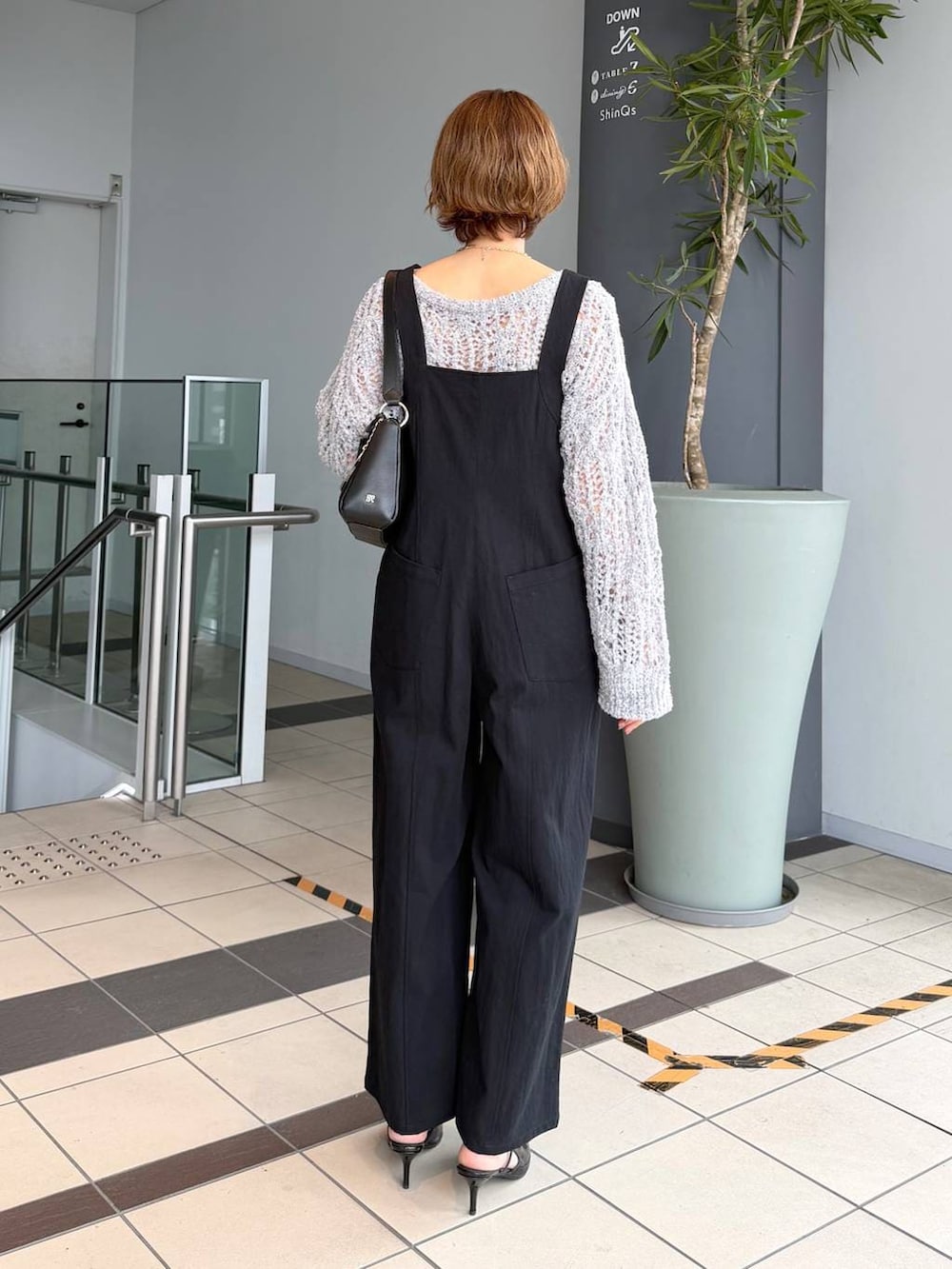 グレー系のニット/セーター、ブラック系のサンダル、ブラック系のショルダーバッグを着用したレディースの春コーディネートの3枚目の写真