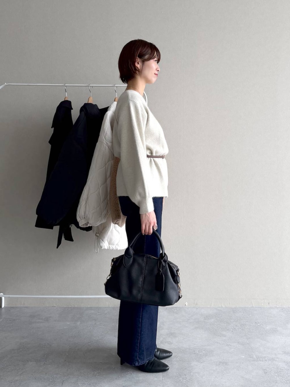 ブルー系のデニムパンツ、ブラック系のボストンバッグ、ホワイト系のナイロンジャケットを着用したレディースの秋コーディネートの6枚目の写真