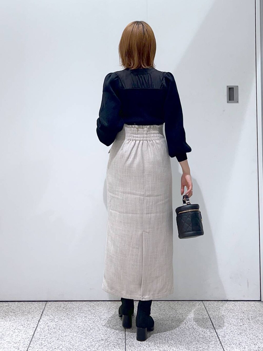 ブラック系のブーツ、ブラック系のショルダーバッグ、ホワイト系のスカートを着用したレディースの秋コーディネートの3枚目の写真