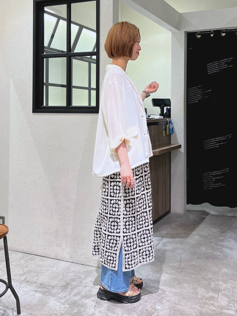 ブルー系のデニムパンツ、ベージュ系のサンダル、ブラック系のショルダーバッグを着用したレディースの夏コーディネートの2枚目の写真