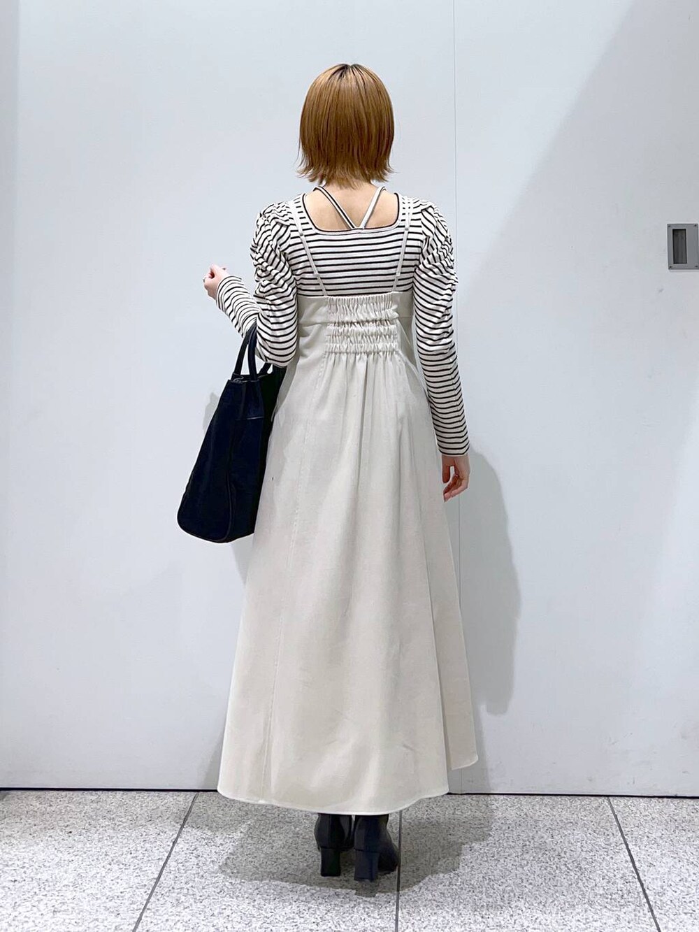 ホワイト系のワンピース、ブラック系のトートバッグ、ホワイト系のTシャツ/カットソーを着用したレディースの冬コーディネートの6枚目の写真