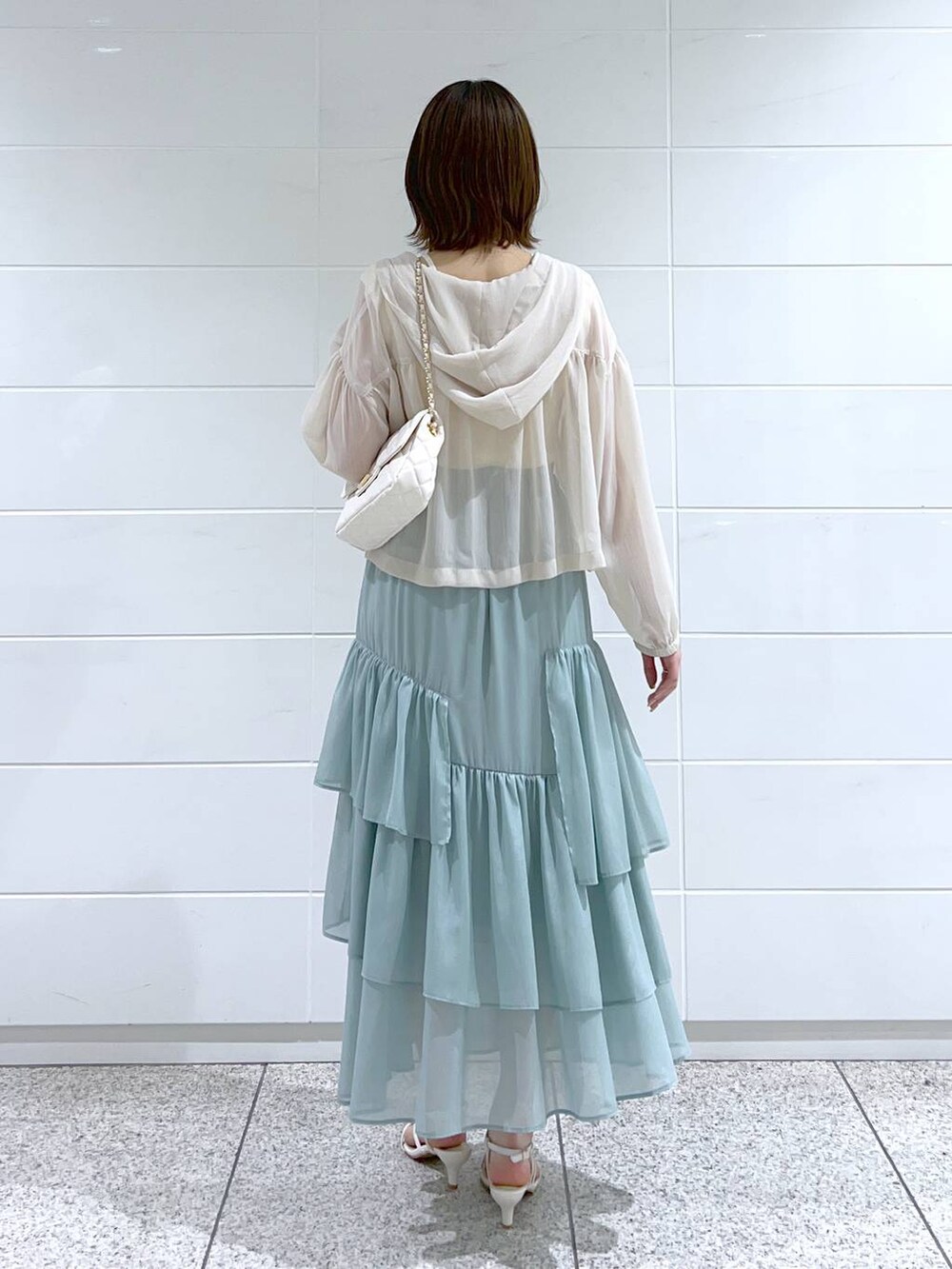 グリーン系のスカート、ホワイト系のショルダーバッグ、ホワイト系のパーカーを着用したレディースの春コーディネートの4枚目の写真