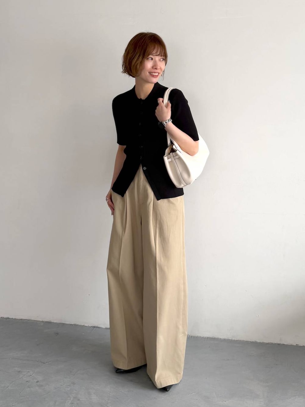 ブラック系のカーディガン/ボレロ、ベージュ系のチノパンツ、ホワイト系のショルダーバッグを着用したレディースの春コーディネートの4枚目の写真