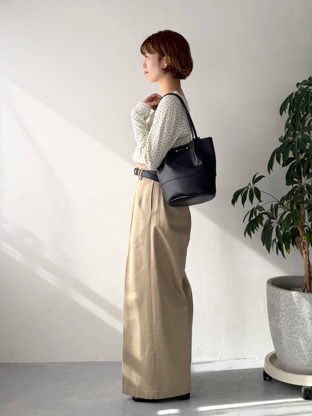 ホワイト系のTシャツ/カットソー、ベージュ系のチノパンツ、ブラック系のトートバッグを着用したレディースの春コーディネートの2枚目の写真